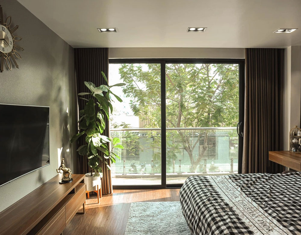 Phòng ngủ của căn hộ 100m2 có cửa kính thông ra ban công